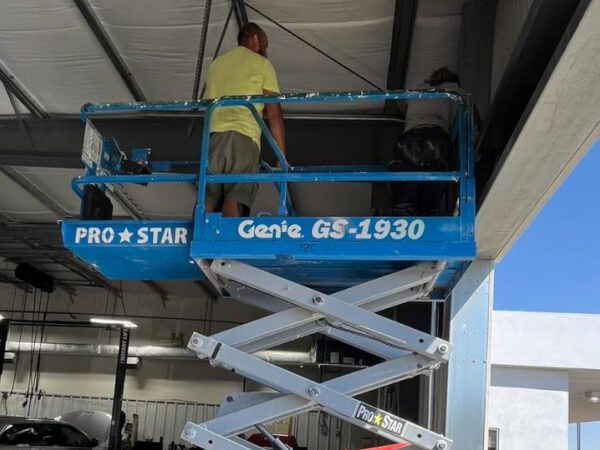 Technicians on a scissor lift installing a commercial security system at a Dallas business