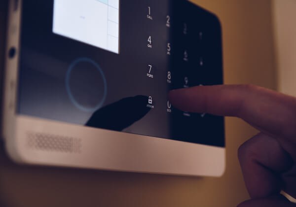 Homeowner arming a monitored home alarm keypad on the wall