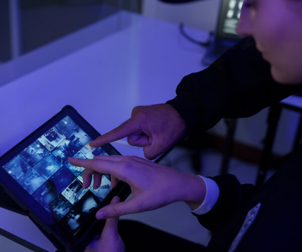 Operator monitoring live security camera feeds on a tablet