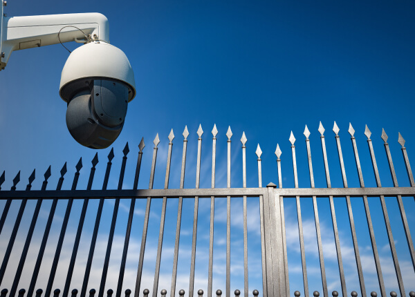 PTZ security camera watching over a gated community fence