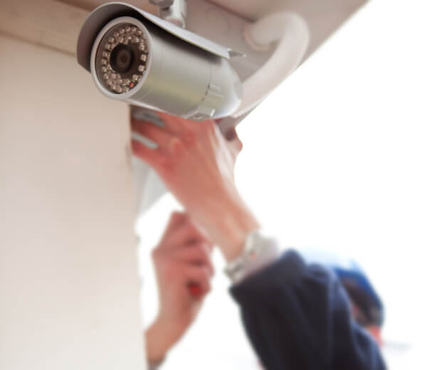 Technician adjusting a commercial security camera on a ceiling