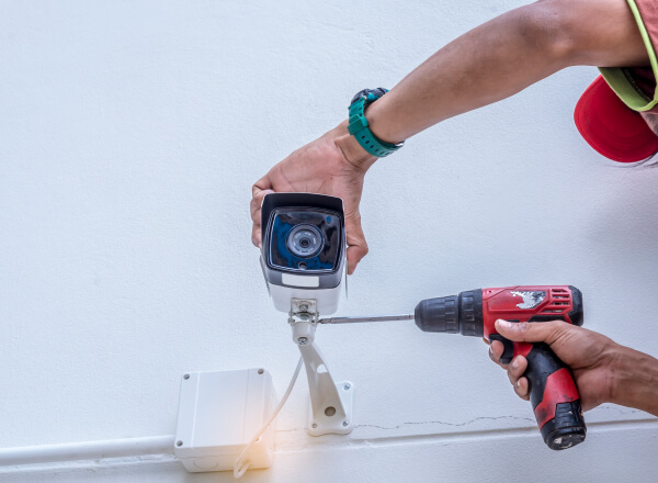 Technician installing a commercial security camera in Plano business